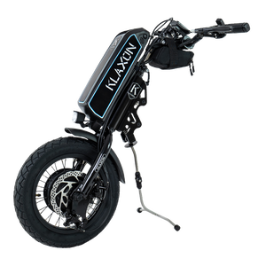 Front view of the Klaxon Klick Power wheelchair handbike power add-on, featuring a 14-inch wheel with a smooth tread tyre, mechanical disc brakes, and an integrated lithium battery, isolated on a white background.