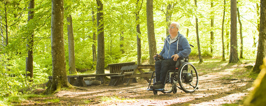 Man in wheelchair driving through woodland