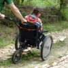 Pushing a girl along a brick path in a wheelchair