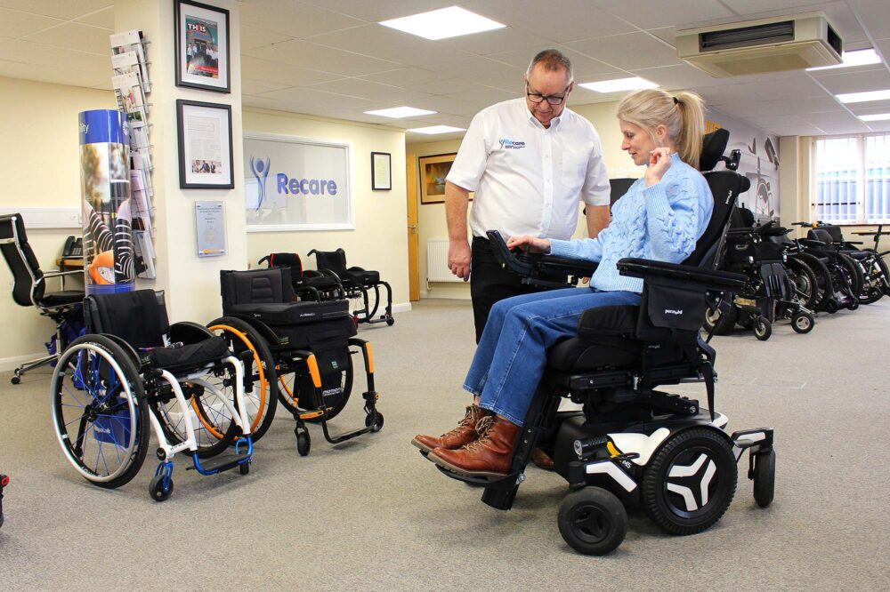 Woman trying out powerchair in showroom with an assessor
