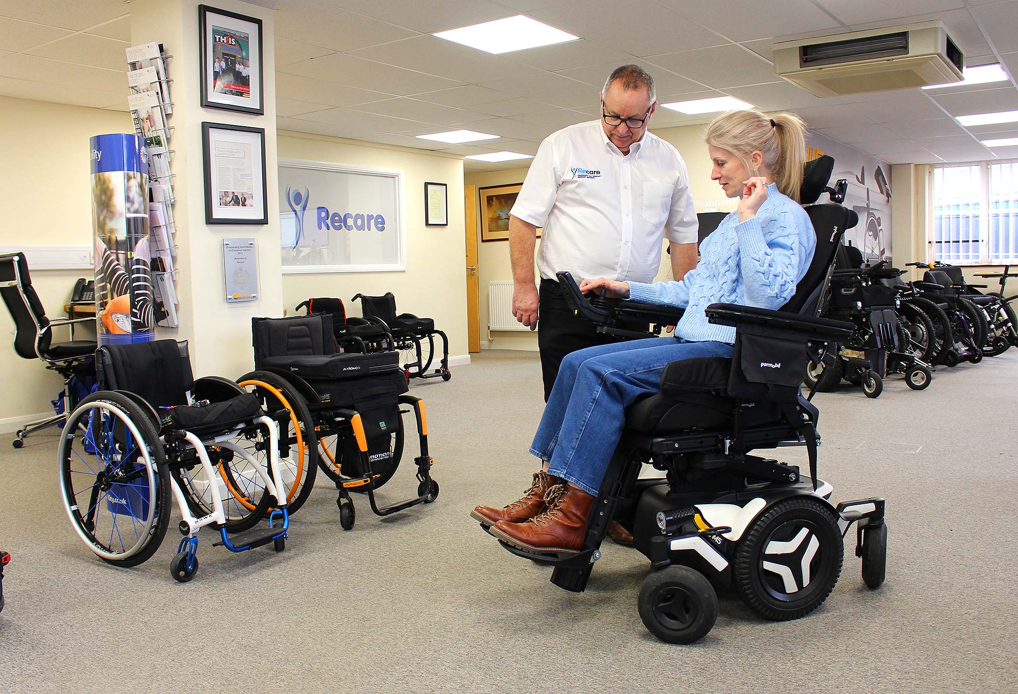 Woman trying out powerchair in showroom with an assessor