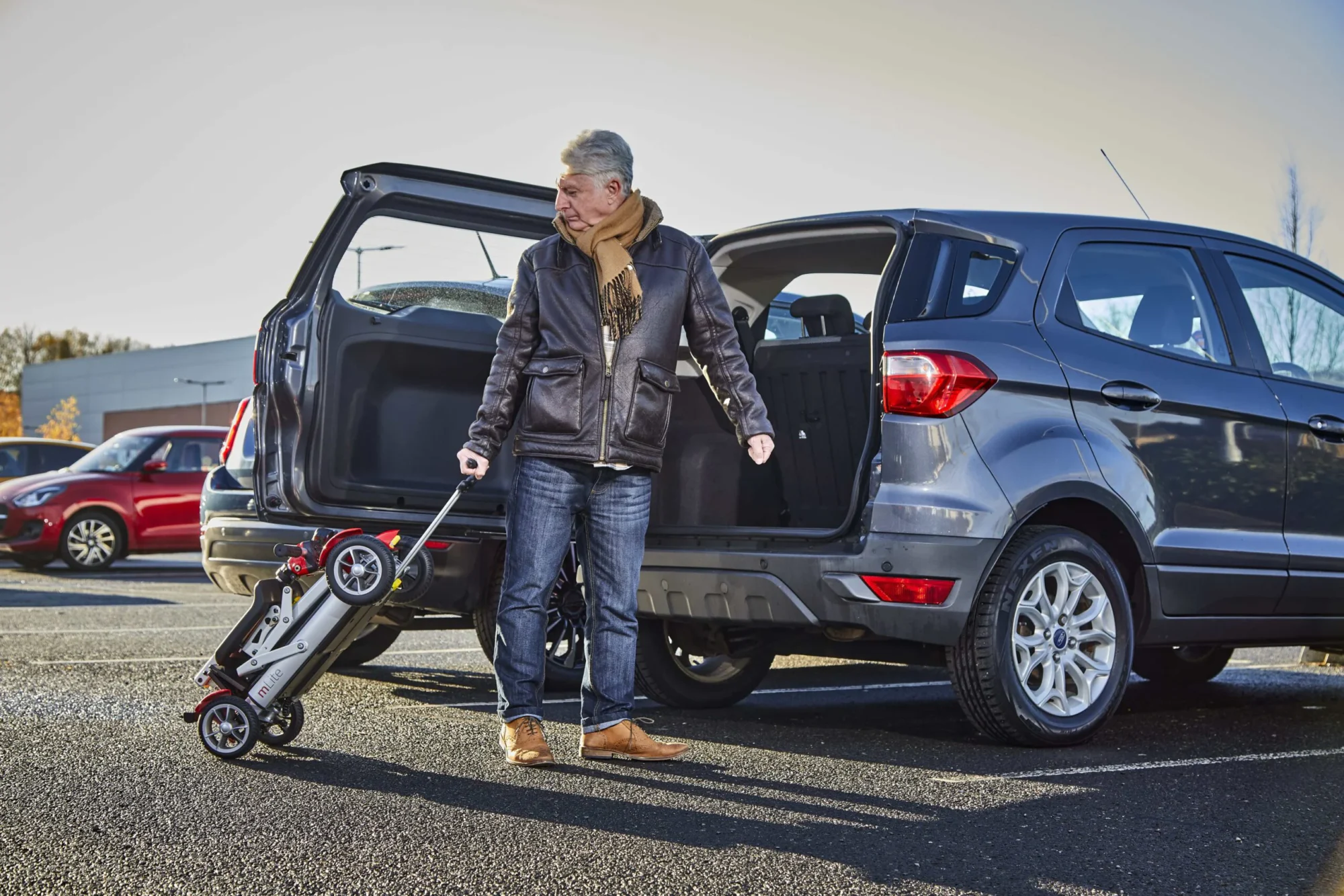 man pulling foldable scooter to his car using an extending handlebar