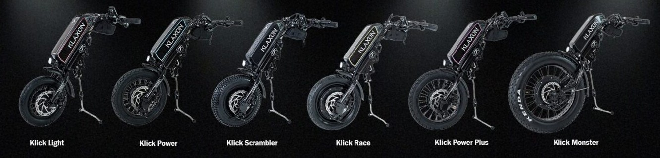 A wide lifestyle banner showcasing a variety of Klaxon Klick wheelchair power handbikes attached to manual wheelchairs, demonstrating outdoor mobility and adventure on a park trail.