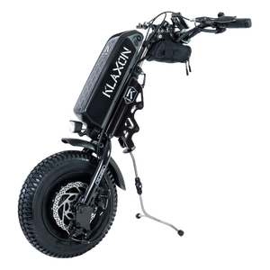 Side profile of the Klaxon Klick Scrambler wheelchair power add-on, featuring a 13.3-inch off-road tire, integrated battery, and the patented Klick linking system for quick attachment to a manual wheelchair, isolated on a white background.