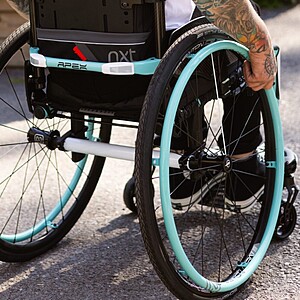 A set of Newton AirGrip handrims by Motion Composites for manual wheelchairs, featuring an ultra-lightweight design and a high-friction, non-peel coating available in various vibrant colors.