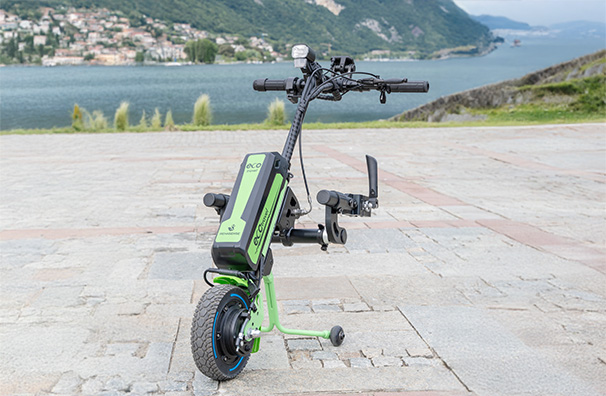 Green Rehasense ECO Travel LX handbike parked on a stone path with a beautiful lake and mountain background.