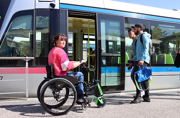 A woman using a Rehasense ECO Travel LX electric handbike to board a modern train, highlighting accessible public transport.