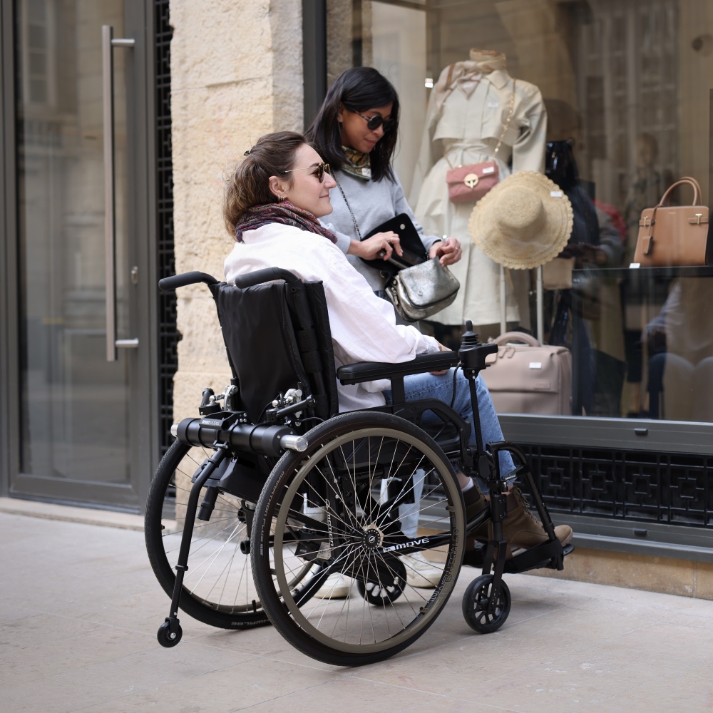 Side profile of a manual wheelchair equipped with the Benoit Systèmes Light Drive 3, highlighting the compact design and how the power add-on maintains the chair's original footprint and maneuverability.