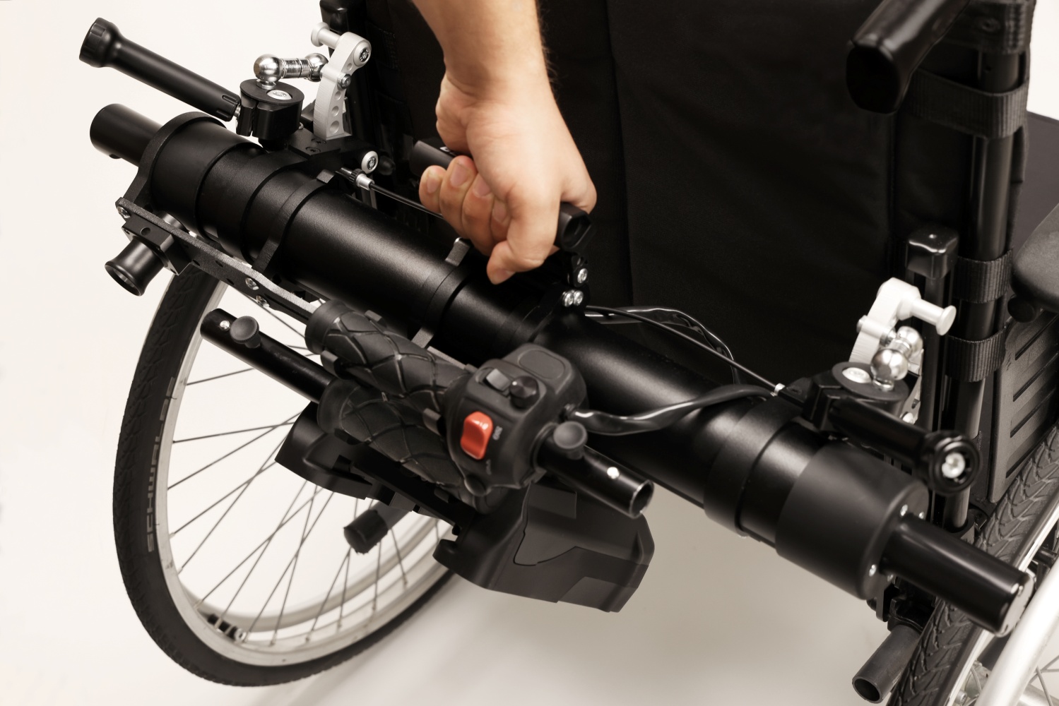A hand uses the integrated top handle to demonstrate the quick-release system for detaching the Light Assist 3 unit from a wheelchair.