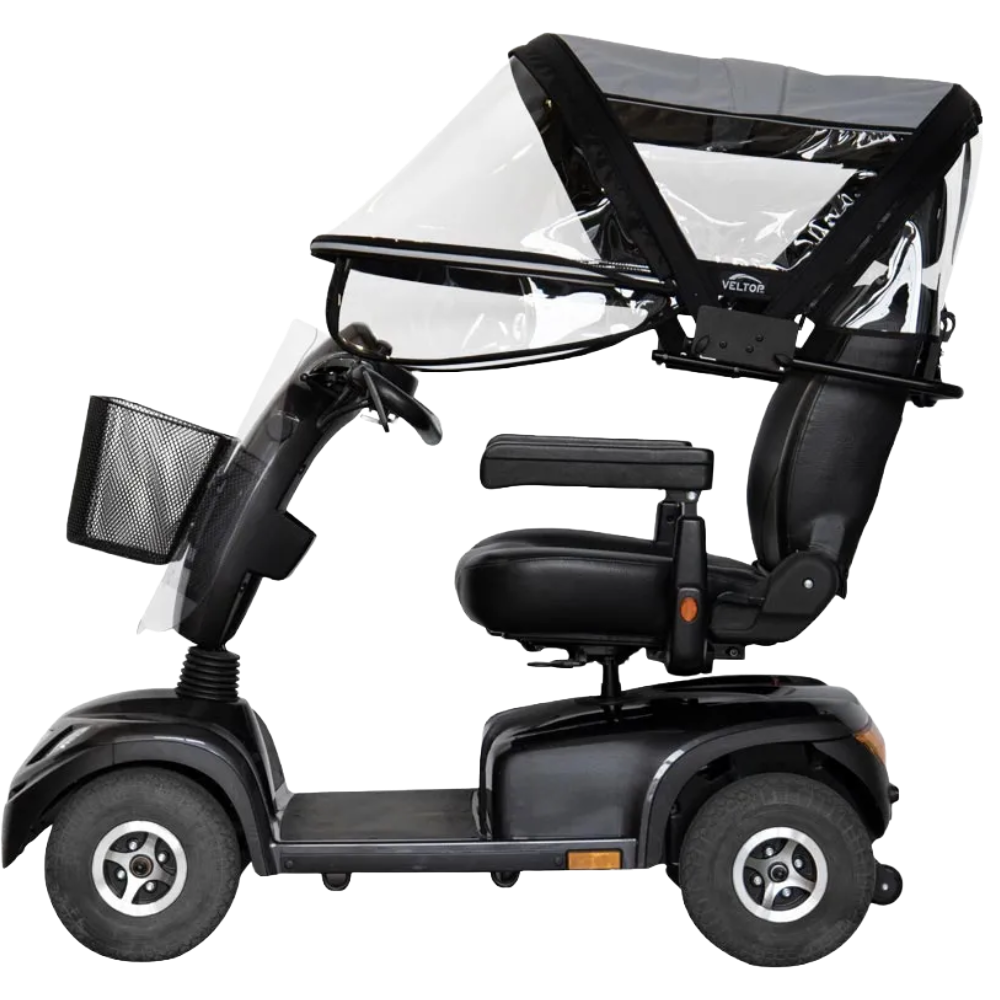 A side-profile view of a black mobility scooter with the Veltop Comfort Mobil-C canopy installed. The image displays the grey overhead fabric and the transparent side and front sections that fully encapsulate the rider's seating area for maximum weather resistance.