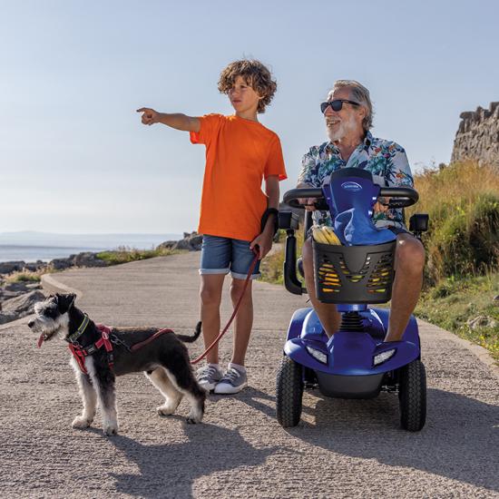 Boy with dog next to a man riding a Leo mobility scooter